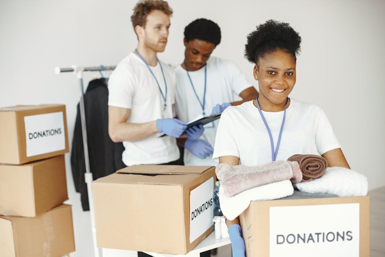 services-01 Group of volunteers smiling while sorting donation boxes indoors for a charity organization.